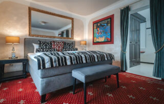 Schlafzimmer im Hotel mit stilvollem Bett, Teppich und Kunstwerk an der Wand, ideal für einen entspannenden Aufenthalt.