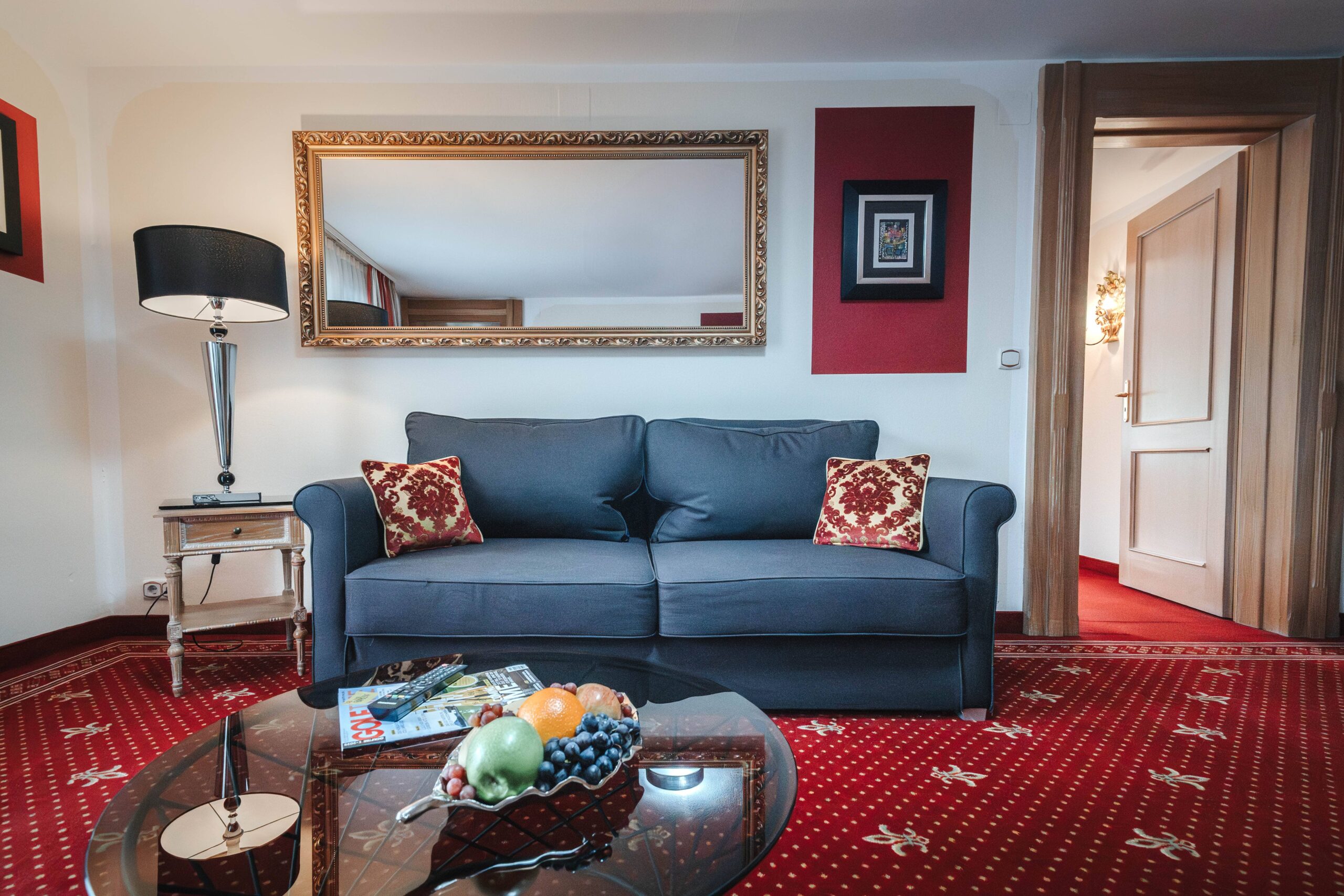 Einladende Sitzecke im Hotelzimmer mit einem grauen Sofa, dekorativen Kissen und einer Obstschale auf dem Tisch im Familienurlaub.