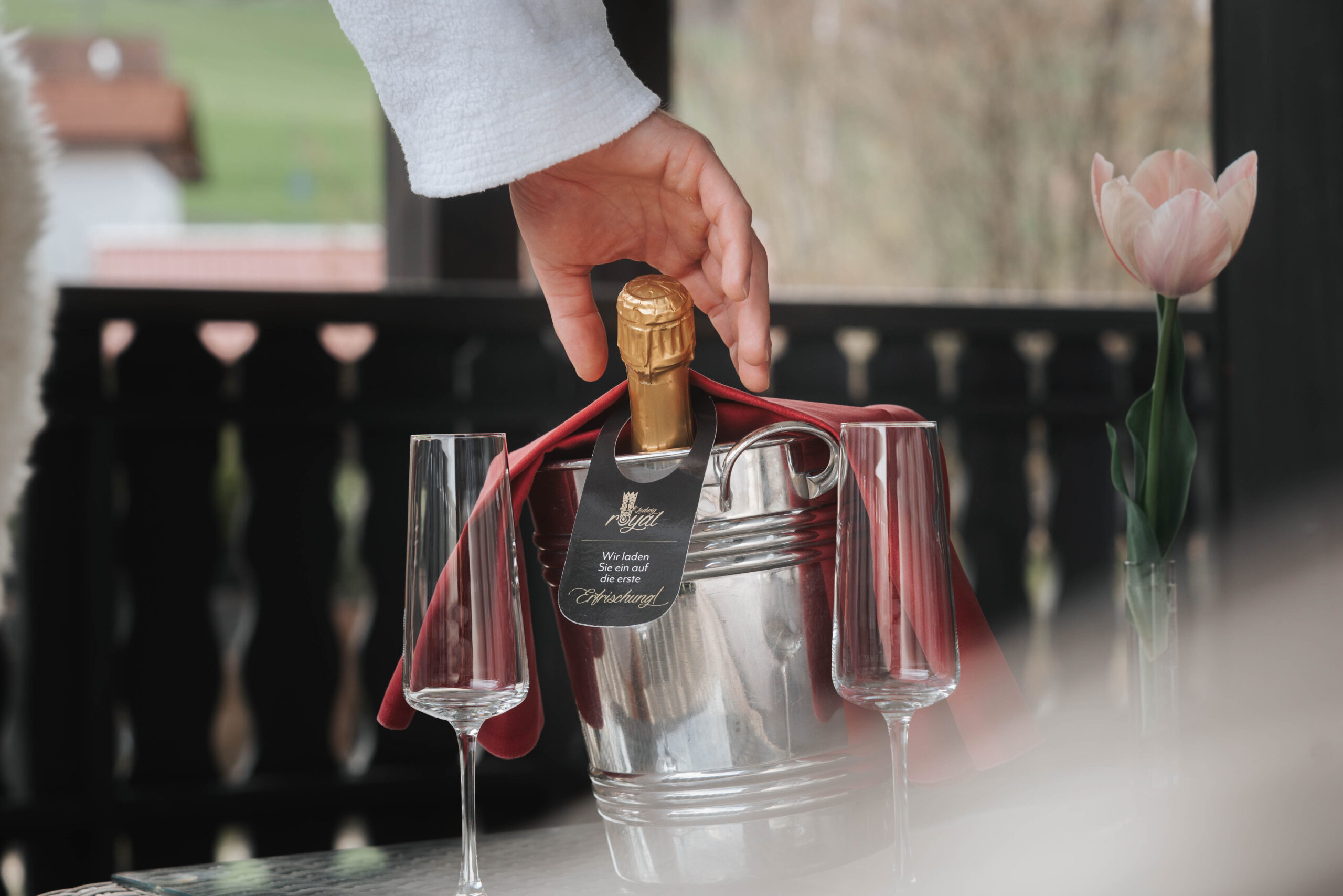 Ein Gast öffnet eine Flasche Sekt in einem Hotel, umgeben von Gläsern und einer stilvollen Dekoration, ideal für einen entspannenden Aufenthalt.