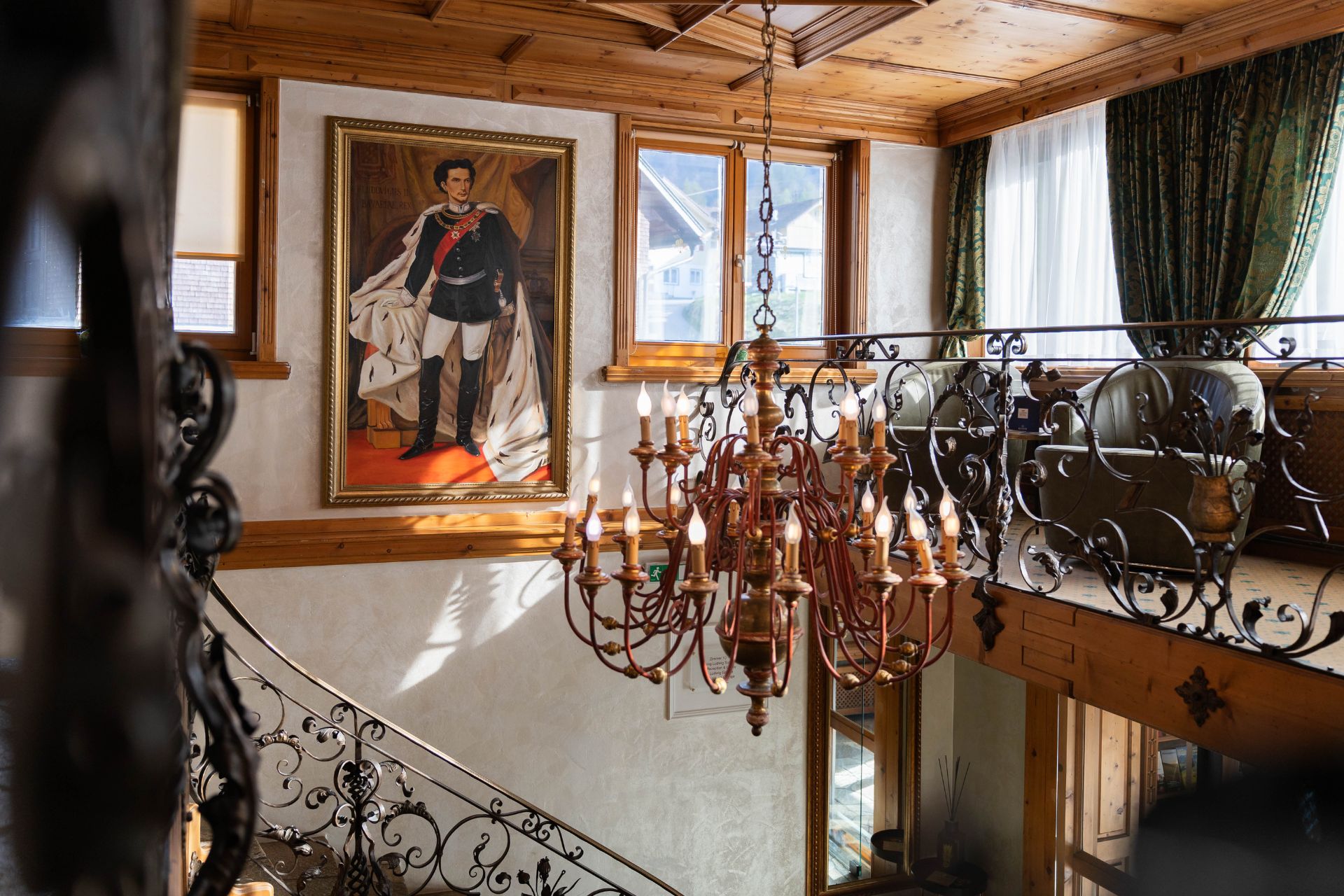Detailansicht der Treppe im Hotel, geschmückt mit einem Gemälde und einem nostalgischen Kronleuchter, ideal für einen stilvollen Aufenthalt.