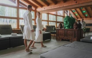 Paar in Bademänteln im Spa-Bereich eines Wellnesshotels, umgeben von Buddhas und entspannendem Ambiente während ihres Wellnessurlaubs.