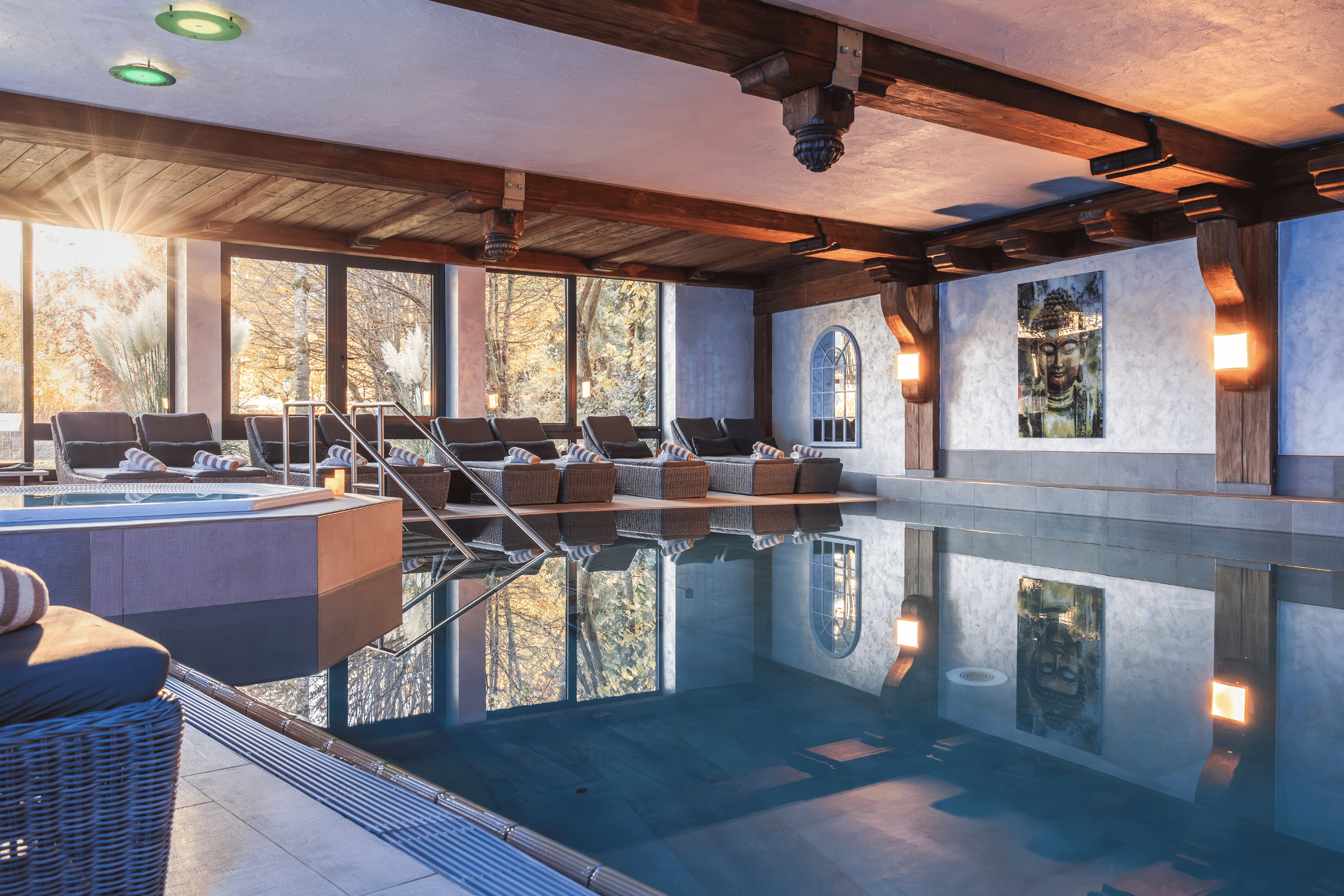 Wellnessbereich im Hotel mit einem Pool und gemütlichen Liegen. Große Fenster bieten Blick ins Freie, ideal für Entspannung.